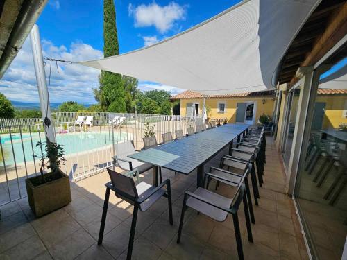 un patio avec une table et des chaises et une piscine dans l'établissement Villa Adhémar 20 personnes, à La Garde-Adhémar