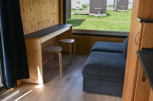a room with a bench and a couch and a window at Tiny House Nature 2 Innenlage - Green Tiny Village Harlesiel in Carolinensiel