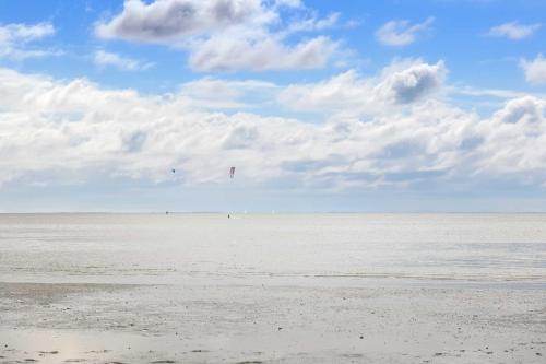 a beach with people flying kites in the sky at Tiny House Nature 2 Innenlage - Green Tiny Village Harlesiel in Carolinensiel