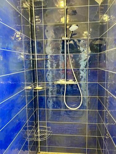 a bathroom with a shower with a blue tile wall at Longère 12 couchages Ploubalay in Ploubalay