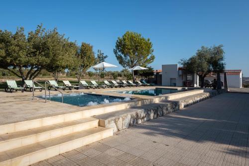 a swimming pool with lounge chairs and trees and a building at Passo do Lobo - Turismo Rural in Moura
