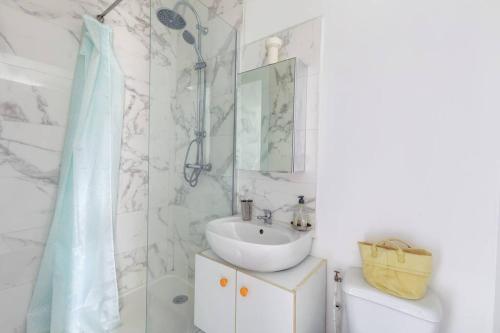 une salle de bain blanche avec un lavabo et une douche dans l'établissement Studio pour 3 - Confort Moderne, Proche Métro, à Paris