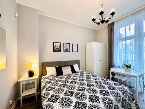 a bedroom with a black and white bed and a window at Studio By The Pier III z balkonem in Sopot