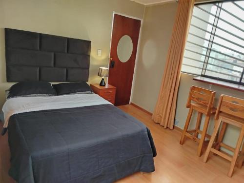 Un dormitorio con una cama, una mesa y un espejo. en Hospedaje Las Lilas Surco, en Lima