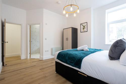 a white bedroom with a bed and a chandelier at 1-Bed Apartment in Manchester by 53 Degrees Property, Ideal for Long Term, Couples or Business Groups! in Worsley