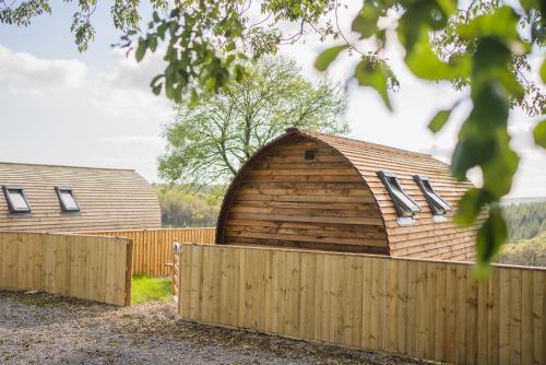 a large wooden barn behind a fence at Rivendell Farm by Wigwam Holidays in Carmarthen