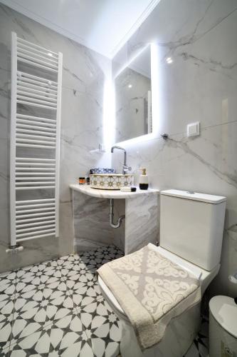 a white bathroom with a toilet and a sink at Favola Golden Beach Villa in Daratso