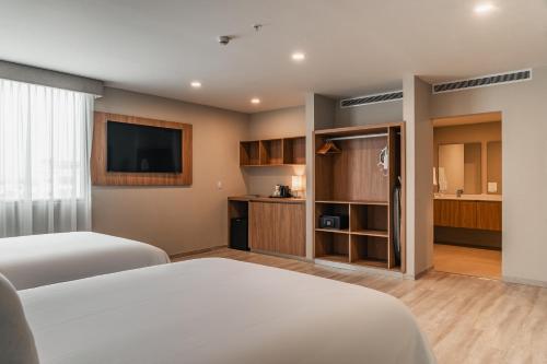 a hotel room with two beds and a flat screen tv at Wyndham Garden Mazatlan Marina in Mazatlán