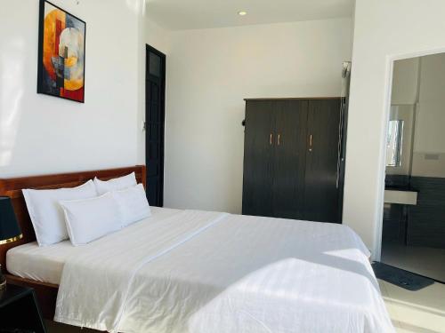 a bedroom with a white bed with a black cabinet at KHÁCH SẠN ROMO in Quang Ngai