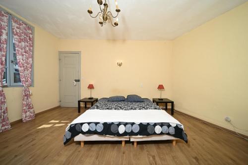 a bedroom with a bed and two tables and a chandelier at Maison de caractère vue sur Neste in Arreau