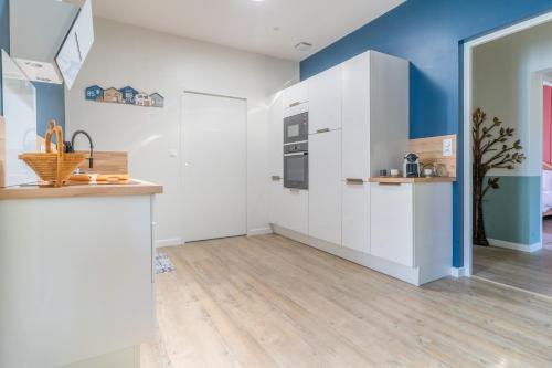 - une cuisine avec des placards blancs et des murs bleus dans l'établissement Mamy Blue - Maison proche Lac de Cazaux, à La Teste-de-Buch