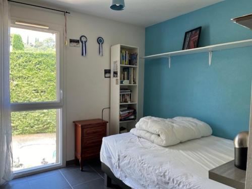 - une chambre dotée d'un mur bleu avec un lit et une fenêtre dans l'établissement Location maisonnette avec jardinet, à Vallauris
