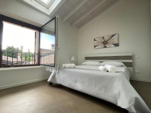 a white bedroom with a bed and a large window at GOMES COMFORT HOUSE in Valeggio sul Mincio