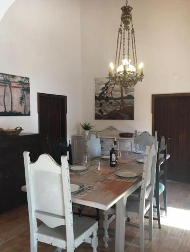 mesa de comedor con sillas blancas y lámpara de araña en San Salvatore, en Querença
