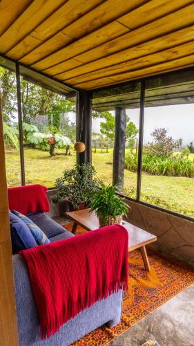 a screened in porch with two couches and a table at Poas Volcano Lodge in Vara Blanca