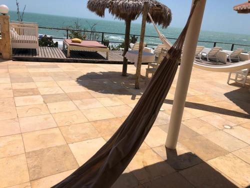 a hammock on a patio with a view of the ocean at Pousada Vila Canoa in Canoa Quebrada