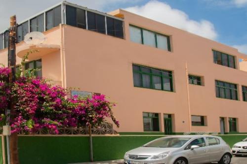 a car parked in front of a building with pink flowers at Bajo Con Playa Tranquila Para Desconectar in Tamaduste