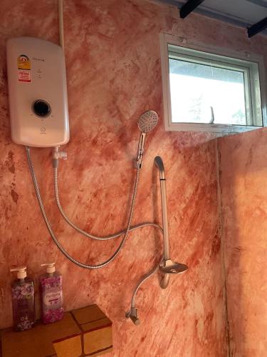 a shower with a hose attached to a wall at บ้านสวนชมดาว ปากช่อง in Pak Chong