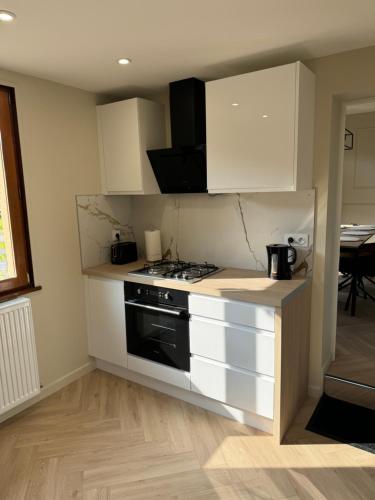 Il comprend une cuisine équipée d'une cuisinière et de placards blancs. dans l'établissement Gîte saint Bernard, à Sedan