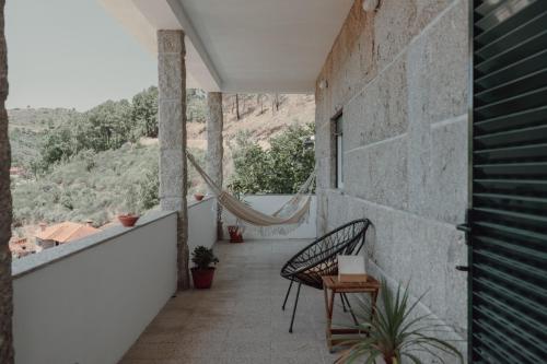 a balcony of a house with a hammock on it at A Casa do Pereira by LovelyStay in Urgueira