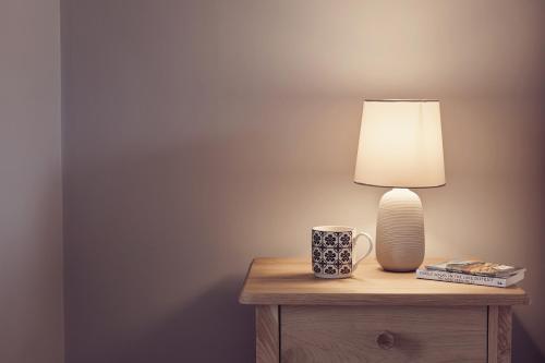 a table with a lamp and a cup on it at Ingleborough in Carnforth
