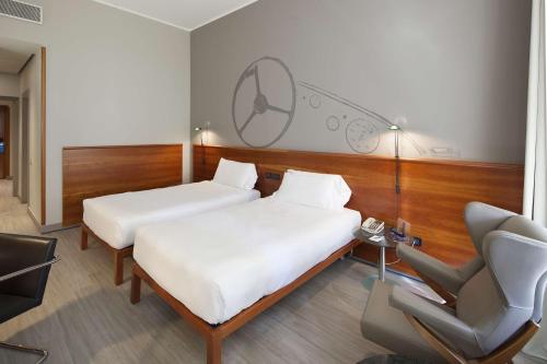 two beds in a room with a desk and a chair at NH Torino Lingotto Congress in Turin
