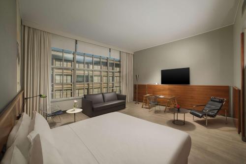 a hotel room with a bed and a flat screen tv at NH Torino Lingotto Congress in Turin