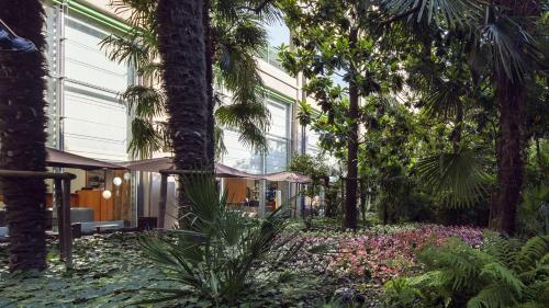 a garden with palm trees and flowers in front of a building at NH Torino Lingotto Congress in Turin