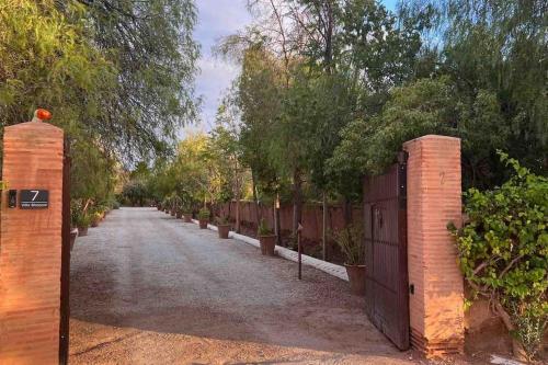 a driveway with a fence and a gate with trees at Villa d architecte Marrakech in Oulad Jellal