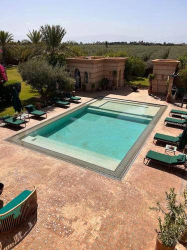a large swimming pool with lounge chairs and a house at Villa d architecte Marrakech in Oulad Jellal