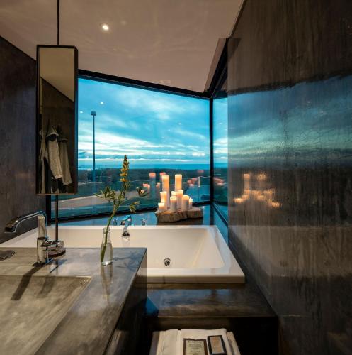 a bathroom with a tub and a large window at Areias do Seixo Villas in Santa Cruz