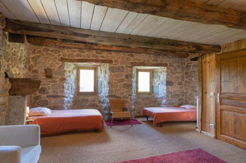 a bedroom with two beds and a stone wall at La Ferme De Chalas in Valgorge