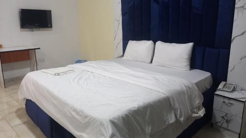 a bed with white sheets and pillows in a room at Tovia Hotel and Suite Limited in Benin City