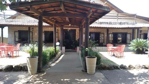 a pavilion with red chairs and tables in front of a building at Hotel Turismo Ltda in Chapada dos Guimarães