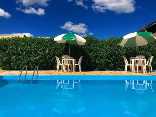 a group of chairs and umbrellas next to a swimming pool at Hotel Turismo Ltda in Chapada dos Guimarães