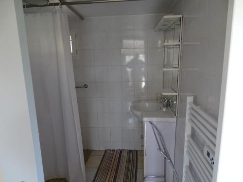 une salle de bain blanche avec un lavabo et une douche dans l'établissement Studio idépendant au rez de chaussée d'une longère terrasse , jardin , mezzanine 1 lit double , 2 matelas sur mezzanine , hauteur limitée pour enfants, à Saint-Ambroix