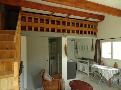 un salon avec un escalier et une cuisine dans l'établissement Studio idépendant au rez de chaussée d'une longère terrasse , jardin , mezzanine 1 lit double , 2 matelas sur mezzanine , hauteur limitée pour enfants, à Saint-Ambroix