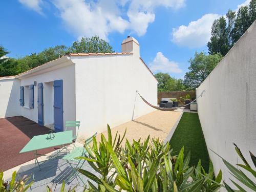 ein weißes Haus mit einem Garten mit Zaun in der Unterkunft Charmante Maison à 500m de la plage in La Tranche-sur-Mer