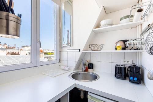 une cuisine blanche avec un évier et une fenêtre dans l'établissement GuestReady - Havre de Paix Parisien pour Deux, à Paris
