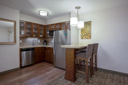 a kitchen with a table and a refrigerator at Staybridge Suites - Gilbert - East Mesa by IHG in Gilbert
