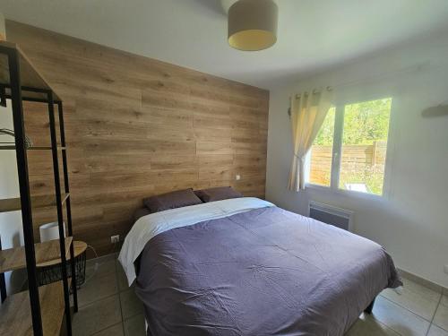 une chambre avec un grand lit avec un mur en bois dans l'établissement Charmante Maison à 500m de la plage, à La Tranche-sur-Mer