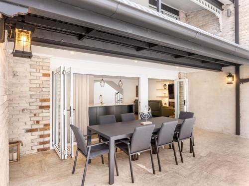 a dining room with a black table and chairs at Riverfront Oasis Spacious 5BR Luxury w 10m Pool in East Hills
