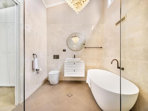 a bathroom with a tub and a toilet and a sink at Riverfront Oasis Spacious 5BR Luxury w 10m Pool in East Hills