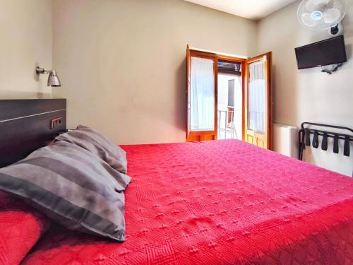 a bedroom with a red bed with a red comforter at Hospedaje La Judería in Segovia