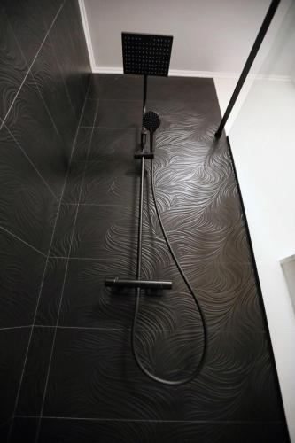 a bathroom with a shower with a black tile floor at Residence Sole 5 by Wave - Apartament luxury 60mp cu terasa si vedere la mare, acces direct pe plaja OhiOhi Beach- Mamaia Nord - Restaurant, Parcare gratuita in Mamaia Sat/Năvodari