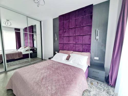 a bedroom with a purple headboard and a bed at Residence Sole 5 by Wave - Apartament luxury 60mp cu terasa si vedere la mare, acces direct pe plaja OhiOhi Beach- Mamaia Nord - Restaurant, Parcare gratuita in Mamaia Sat/Năvodari