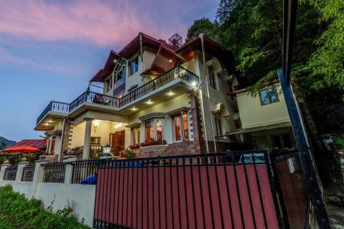 a house with a red fence in front of it at ELIVAAS 3 BHK with Entertainment lounge - The Meadow in Nainital