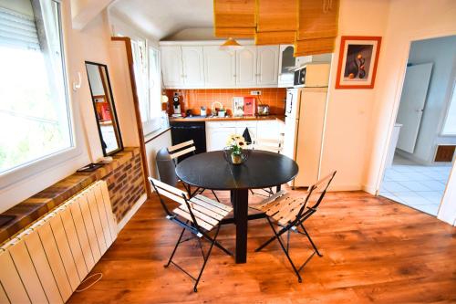 une cuisine avec une table et des chaises dans une pièce dans l'établissement Le Jardin Paisible Beaumontois, à Beaumont-sur-Oise