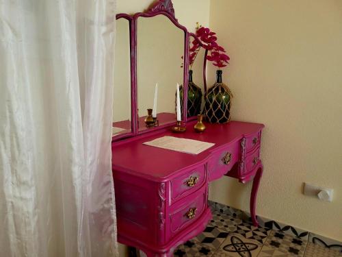 a pink dresser with a mirror and flowers on it at Quinta da Choupana in Tomar