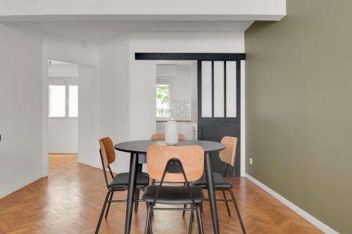 une salle à manger avec une table et des chaises noires dans l'établissement Sublime appartement avec Parking Paris 17 Wagram, à Paris